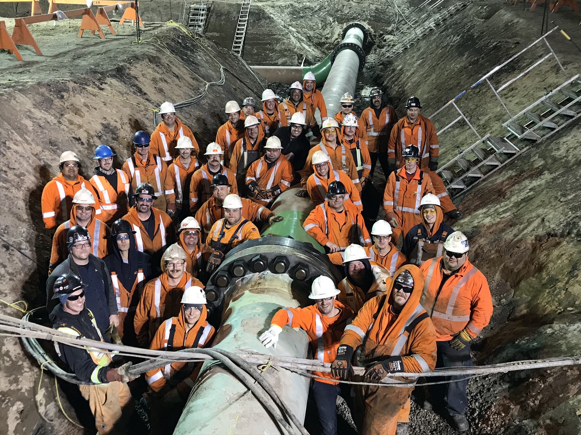 PIpeline construction workers and pipe in trench